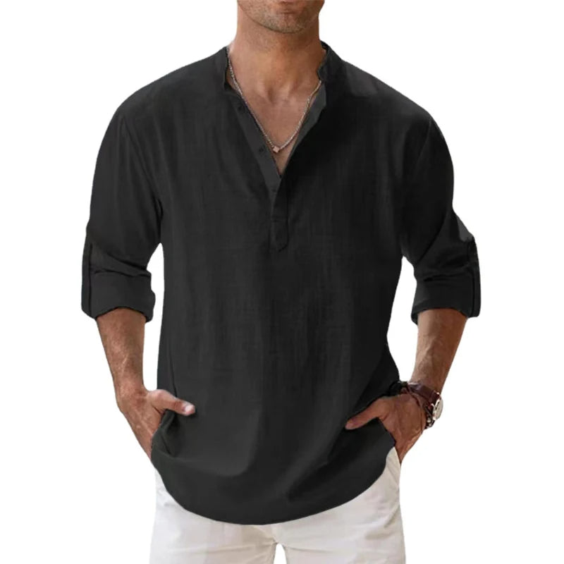Mann trägt das lockere Henley-Shirt in Schwarz mit Stehkragen und hochgekrempelten Ärmeln, dazu weiße Hose. 7