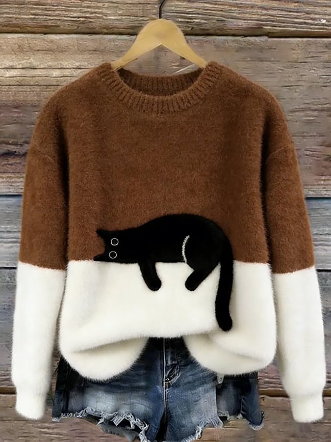 Flauschiger Pullover in Braun mit weißem Unterteil und aufgenähter schwarzer Katze, an Holzbügel vor Holzwand 9