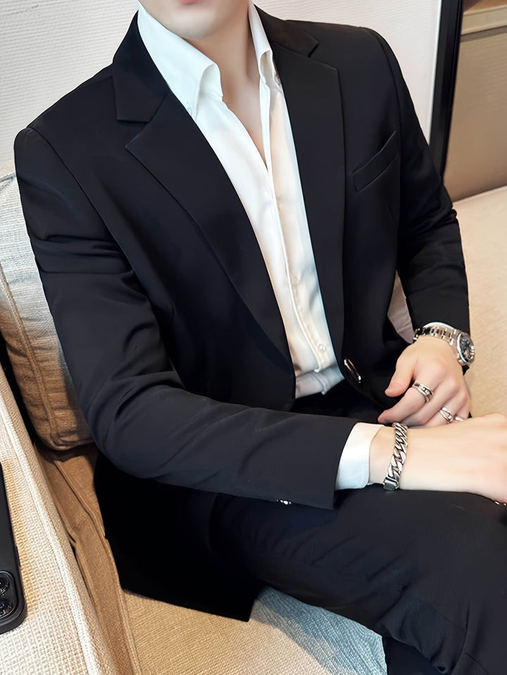 Mann im schwarzen Anzug mit weißem Hemd, sitzt auf Sofa, elegante Herrenmode, Business-Look.