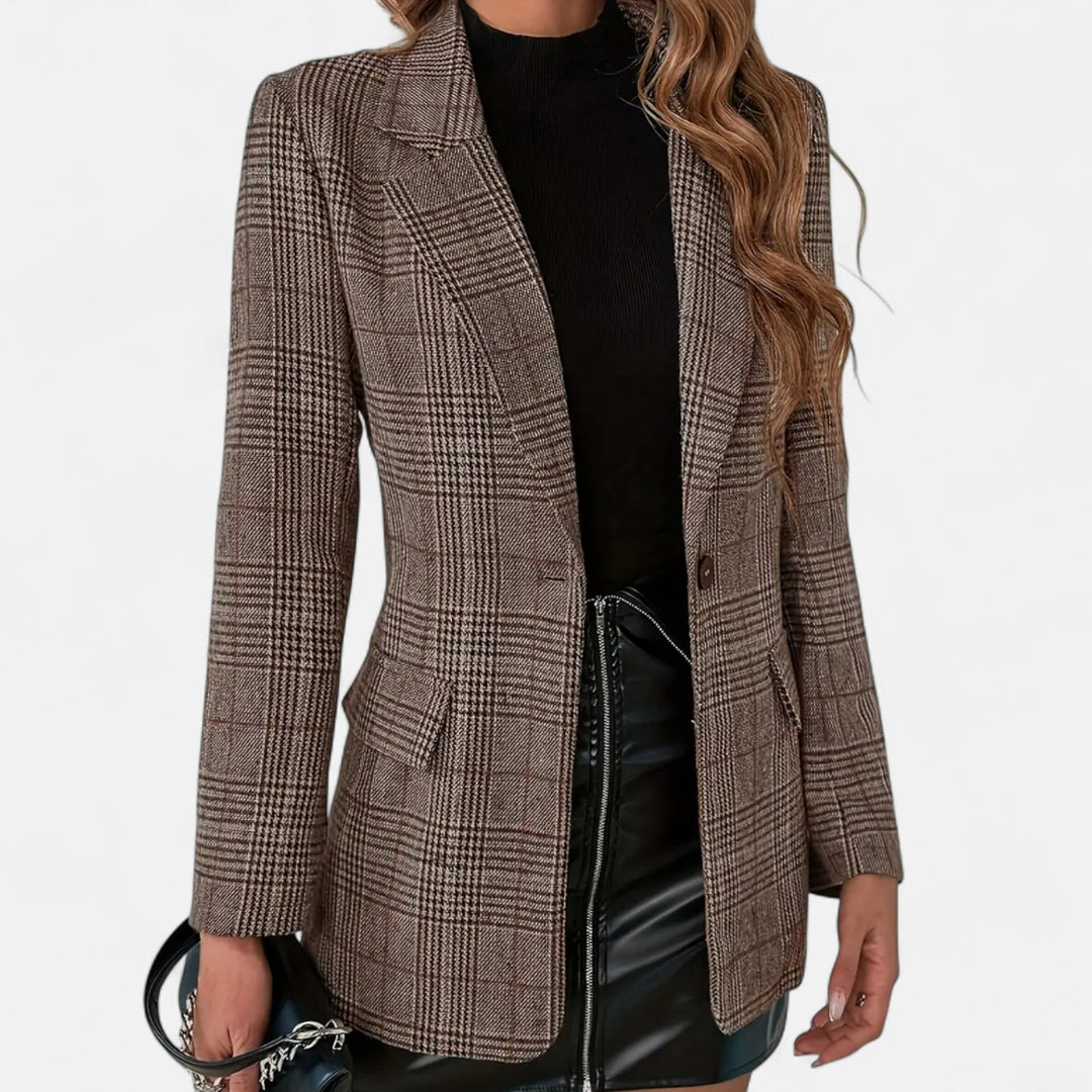 Frontansicht des karierten Blazers an einem Model, getragen zu schwarzem Rollkragenoberteil und schwarzem Lederrock, mit Knopf und Klappentaschen. 1