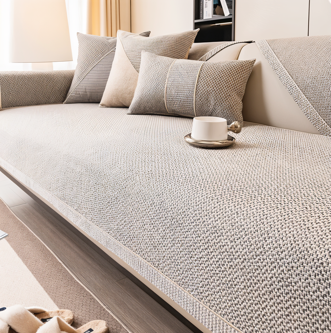 Beige-grau meliertes Sofa-Überwurf-Tuch mit Webstruktur auf einem Sofa, dazu Kissen und eine weiße Tasse im Wohnzimmer. 1