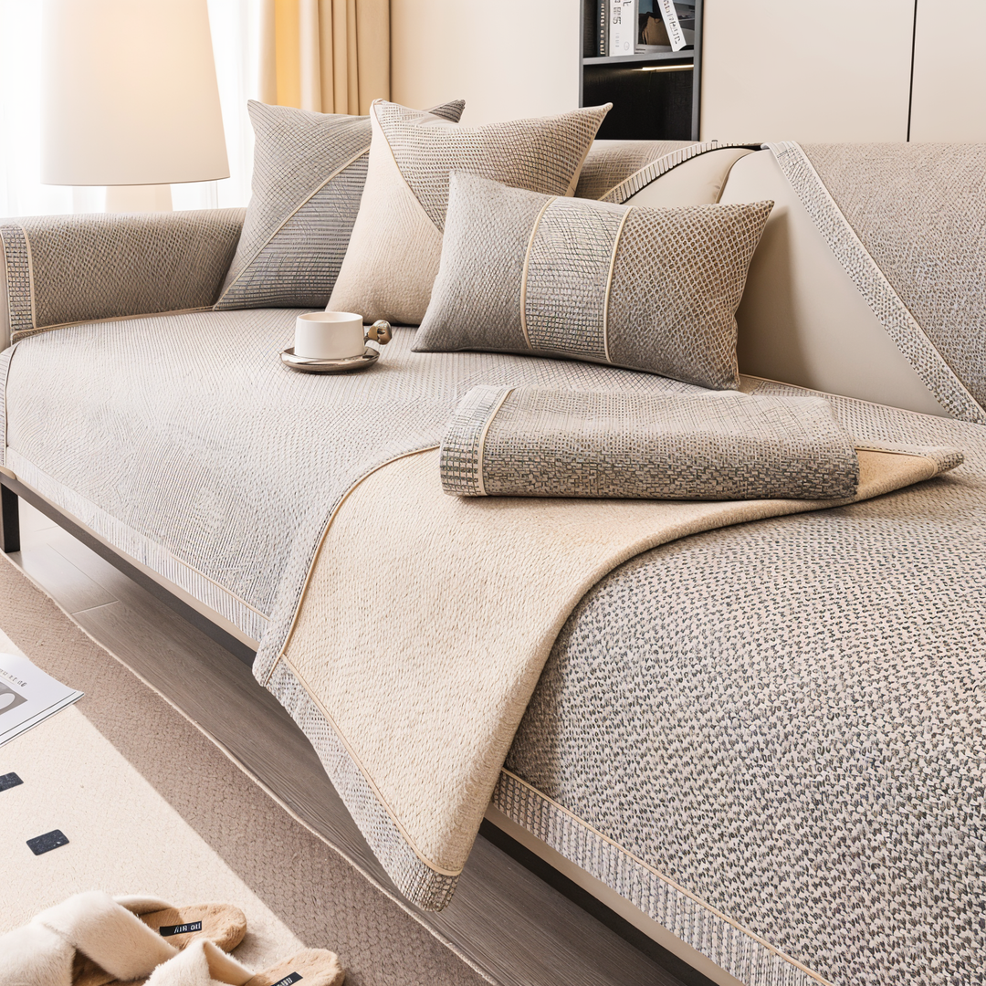 Sofaschutz in Beige-Grau, mit umgeschlagener Ecke und aufgelegtem gefaltetem Stück, das die glatte helle Unterseite zeigt. 3