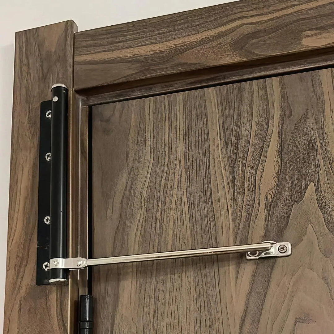 Nahaufnahme eines schwarzen Türschließers mit silbernem Arm an einer dunklen Holztür 3