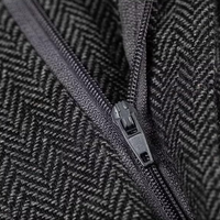 Schwarzer Reißverschluss auf grauem Fischgrätstoff, Nahaufnahme, Textil, Modeaccessoire.