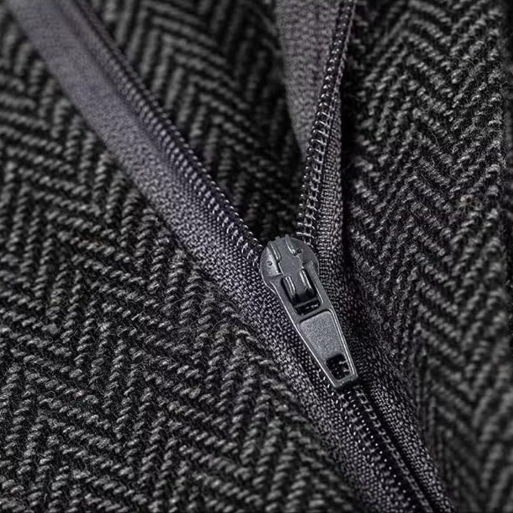 Schwarzer Reißverschluss auf grauem Fischgrätstoff, Nahaufnahme, Textil, Modeaccessoire.