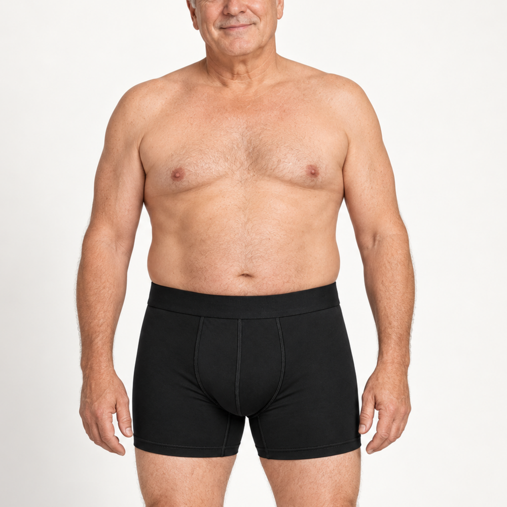 Älterer, lächelnder Mann trägt die schwarze Boxershorts mit Eingriff-Naht frontal vor weißem Hintergrund. 2