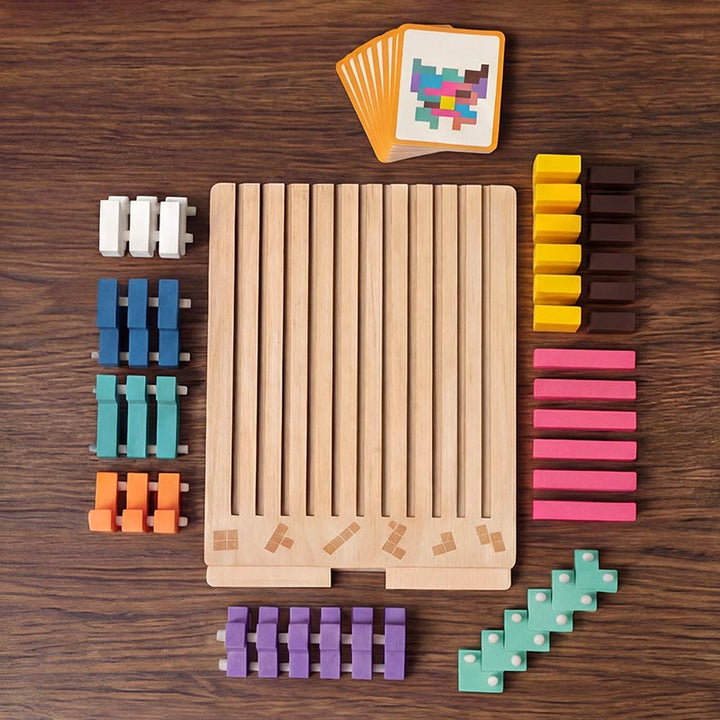 Draufsicht auf dem Holztisch: Spielbrett mit Schlitzen, alle Bausteine nach Farben sortiert und ein Stapel Vorlagekarten. 2