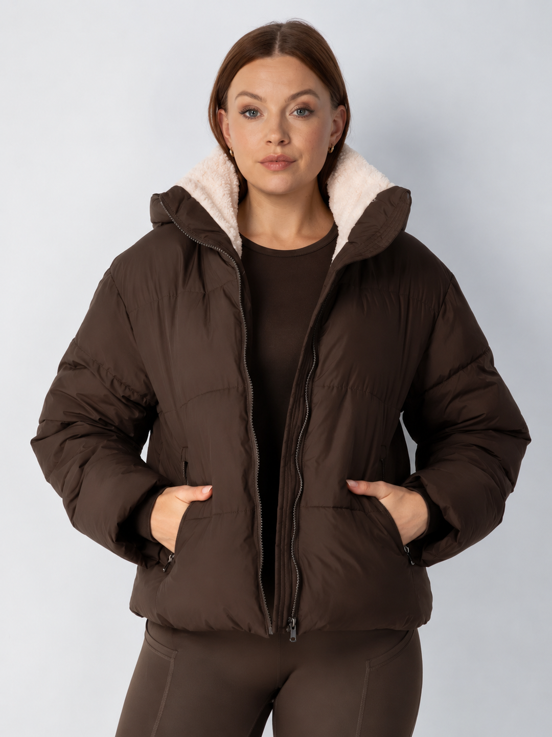 Frontansicht der braunen Steppjacke mit cremefarbenem Fleecefutter, Hände in den Taschen 14