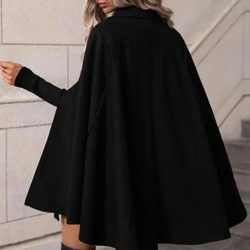 Frau in schwarzem Cape-Mantel, elegantes Design, Herbstmode, Treppenhaus-Hintergrund.
