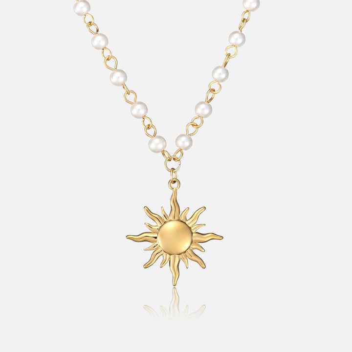 Frontansicht der Halskette mit goldenem Sonnenanhänger an einer Kette aus kleinen weißen Perlen und goldfarbenen Gliedern auf hellem Hintergrund. 1