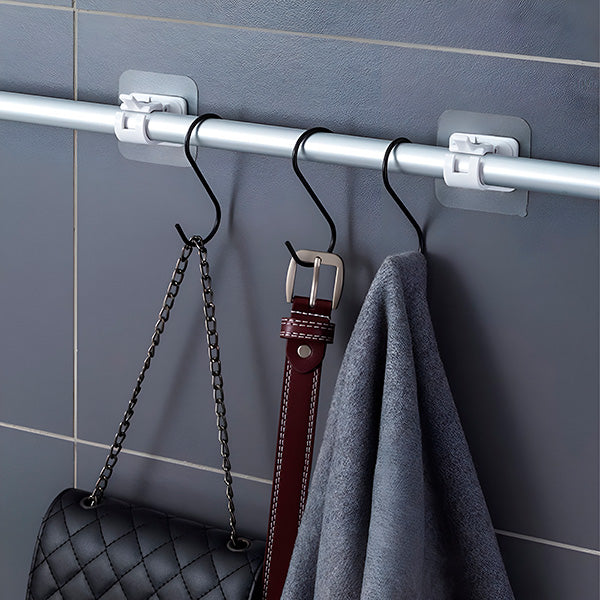 Stange an zwei Halterungen mit schwarzen S-Haken, an denen eine gesteppte Handtasche, ein brauner Gürtel und ein graues Tuch hängen. 5