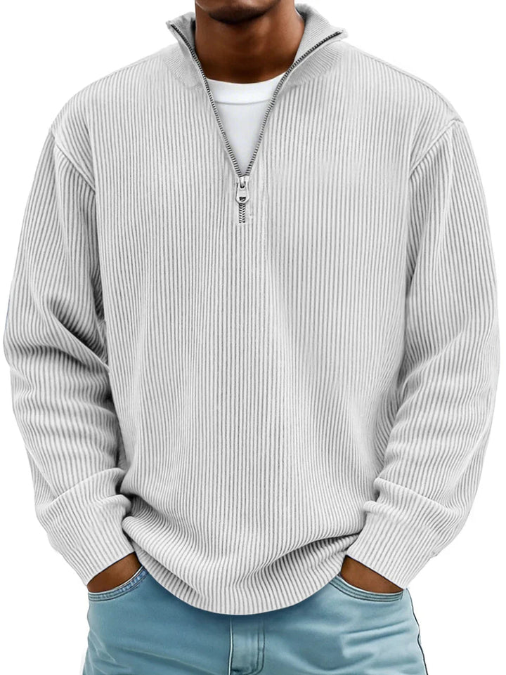 Mann trägt den Rippstrickpullover in Weiß mit feiner Rippstruktur, Hände in den Taschen einer hellblauen Jeans 6