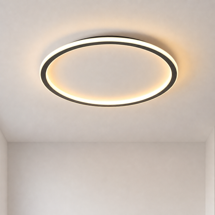 Eingeschaltete runde Deckenleuchte mit schwarzem Ring und warmweißem Licht an einer hellen Zimmerdecke, frontale Gesamtansicht. 1