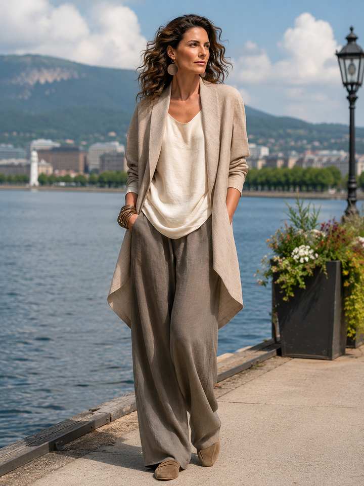 Model trägt das dreiteilige Set draußen an einer Uferpromenade mit See, Bergen und Blumenkübel im Hintergrund. 7