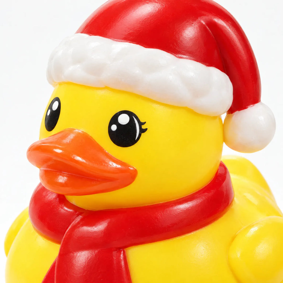 Nahaufnahme einer gelben Gummiente mit roter Weihnachtsmütze und rotem Schal, die glänzende Oberfläche und die orangefarbenen Schnabel-Details sind gut zu erken 4