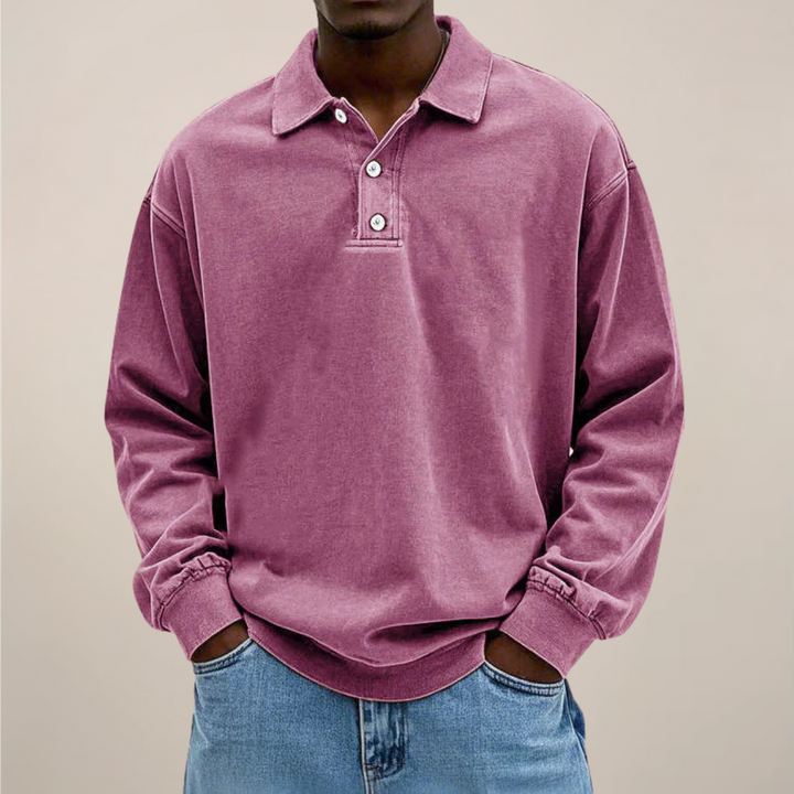 Model im lockeren Poloshirt in Rosa-Violett mit Knopfleiste und Kragen, kombiniert mit heller Jeans. 10