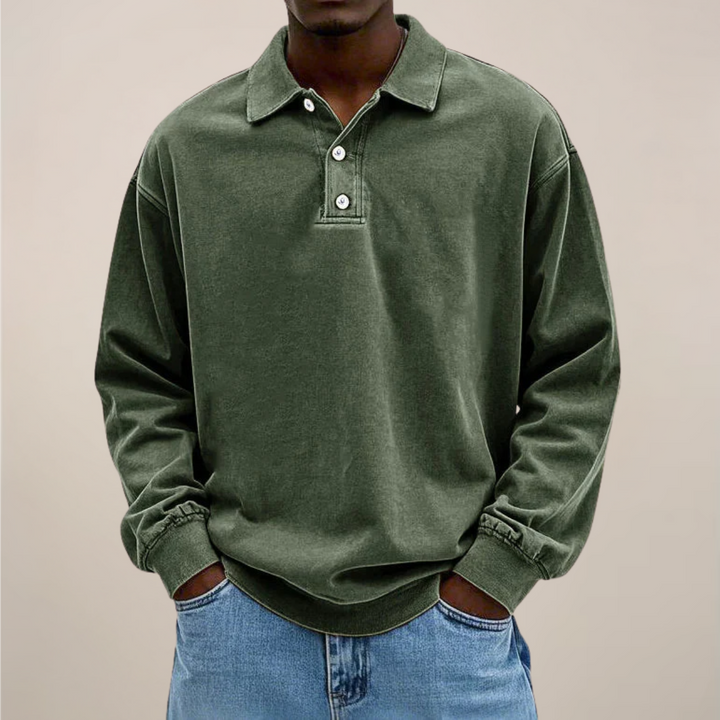 Frontansicht des Langarm-Poloshirts in Olivgrün, getragen von einem Model mit Jeans und Händen in den Taschen. 2
