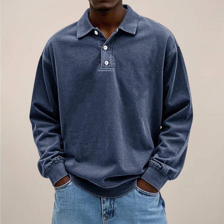 Model im lockeren Poloshirt in dunklem Graublau, Hände in den Taschen der hellen Jeans. 5