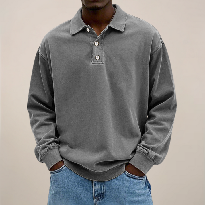 Frontansicht des lockeren Langarm-Poloshirts in Grau, getragen mit heller Jeans, Details wie Kragen und Bündchen sichtbar. 7