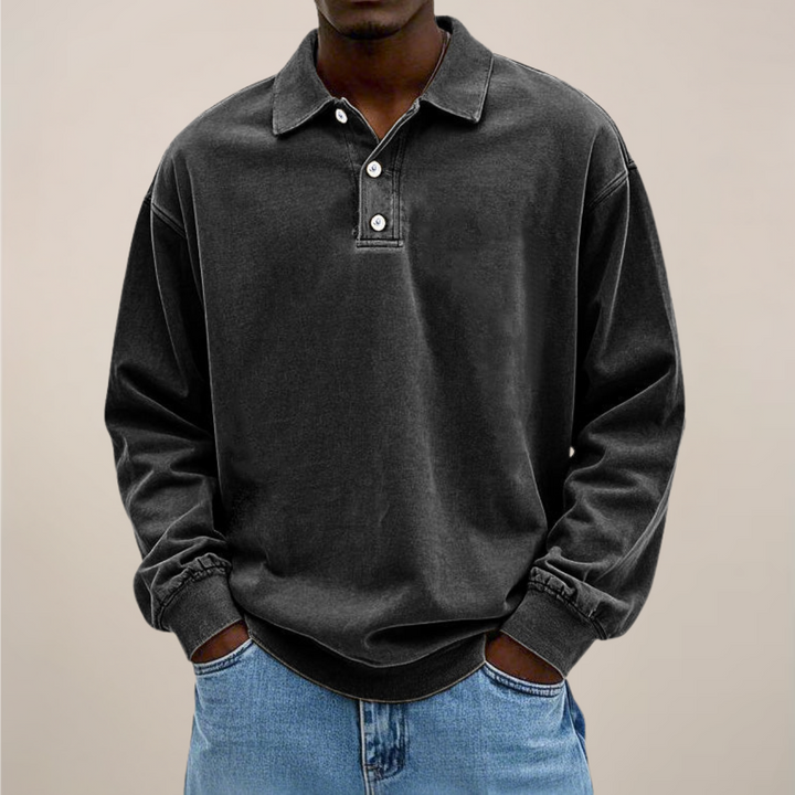 Model trägt das Poloshirt in Schwarz mit drei Knöpfen am Kragen und gerippten Bündchen, dazu Jeans. 8