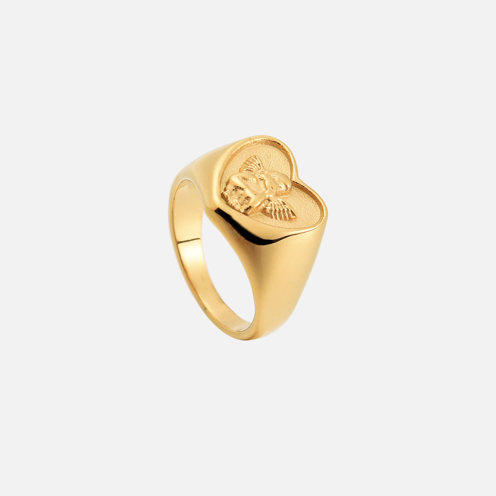 Dasselbe goldfarbene Herzring-Modell von oben schräg fotografiert, mit Blick auf die Ringschiene und das Engelrelief. 2