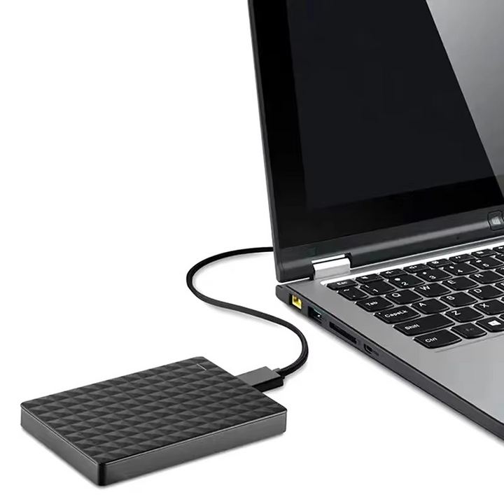 Festplatte neben einem aufgeklappten Laptop, mit dessen USB-Anschluss über ein dünnes Kabel verbunden 5