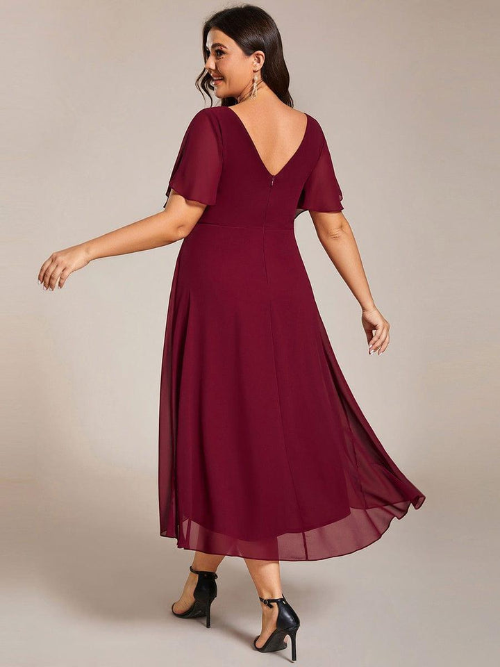 Rückansicht des weinroten Kleids am Plus-Size-Model mit tiefem V-Rückenausschnitt, Reißverschluss und wehendem Chiffonsaum. 50