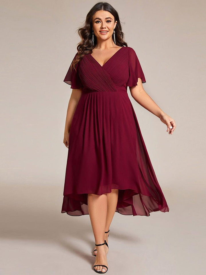Plus-Size-Model im weinroten Kleid mit V-Ausschnitt, Flatterärmeln und Hoch-Tief-Saum, Vorderansicht mit langen Ohrringen. 49