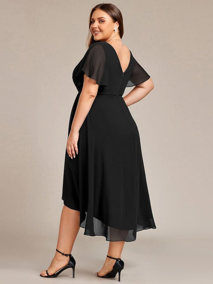 Curvy Model im schwarzen Kleid von hinten, über die Schulter lächelnd, mit tiefem V-Rückenausschnitt, Reißverschluss und halbtransparenten Ärmeln. 27