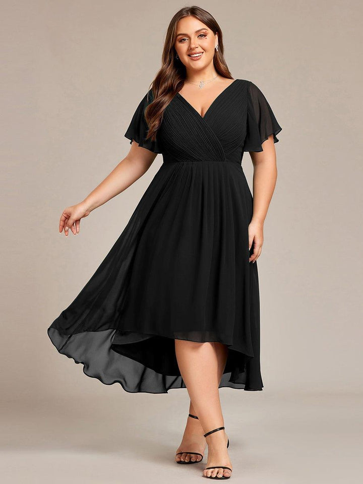 Curvy Model im schwarzen Chiffonkleid mit Flatterärmeln und schwarzen Riemchensandaletten, der Rock schwingt und zeigt den Hoch-Tief-Saum. 26