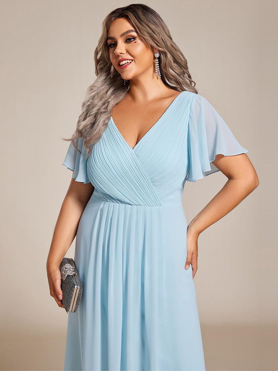 Nahaufnahme des hellblauen Kleids am Curvy Model: Plisseeoberteil, V-Ausschnitt, Flatterärmel und Clutch in der Hand. 91