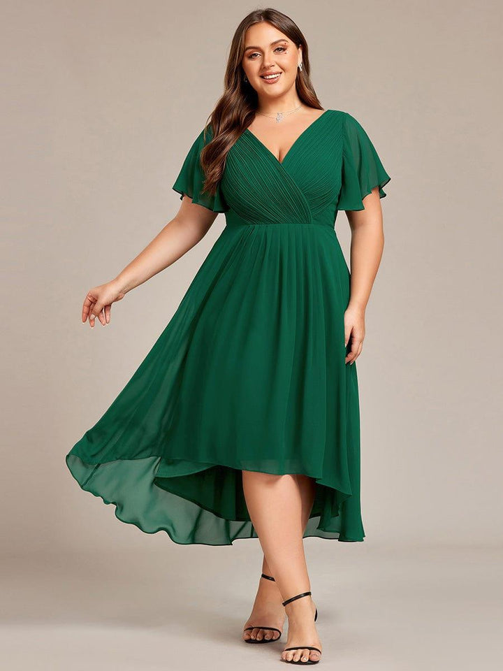 Curvy Model im dunkelgrünen Chiffonkleid mit V-Ausschnitt und Flatterärmeln, schwarze Riemchensandaletten, der Rock schwingt mit Hoch-Tief-Saum. 36