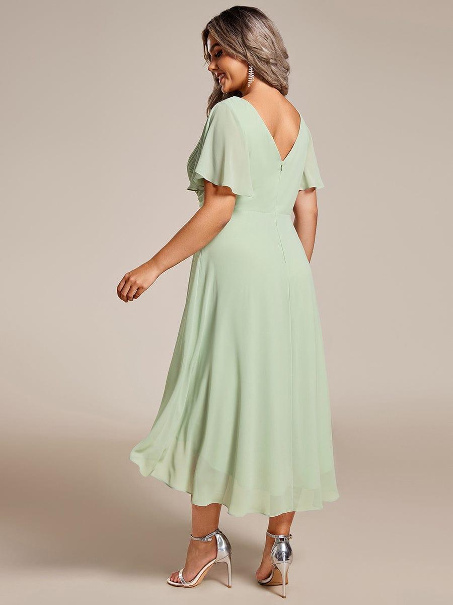 Rückansicht des mintgrünen Kleids am Curvy Model: tiefer V-Rückenausschnitt mit Reißverschluss und schwingender Chiffonsaum. 82