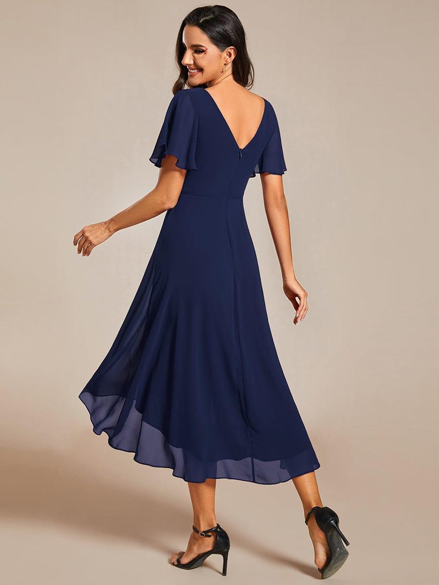 Rückansicht in Marineblau mit tiefem V-Rückenausschnitt, Reißverschluss und fließendem Chiffon-Saum, Model schaut lächelnd über die Schulter. 2