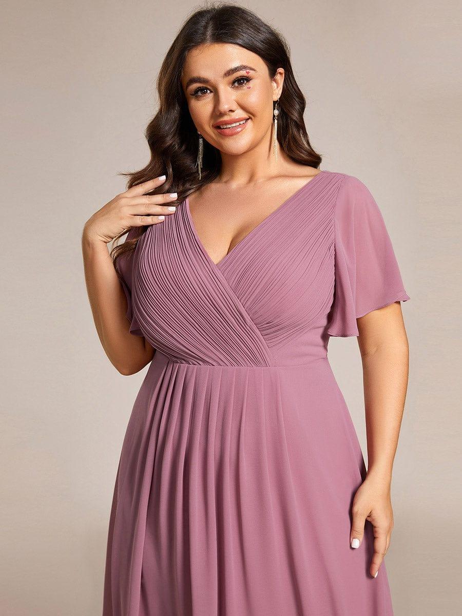 Nahaufnahme des Oberteils am Curvy-Model: feine Raffungen in Wickeloptik, V-Ausschnitt und weiter Flatterärmel am mauvefarbenen Chiffonkleid. 65
