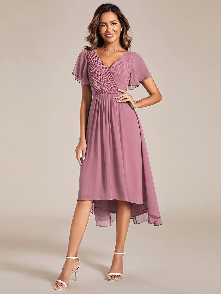 Model im altrosa Chiffonkleid mit Wickelausschnitt, Flatterärmeln und Hoch-Tief-Saum, Hand in der Hüfte, weiße Riemchensandalen. 58
