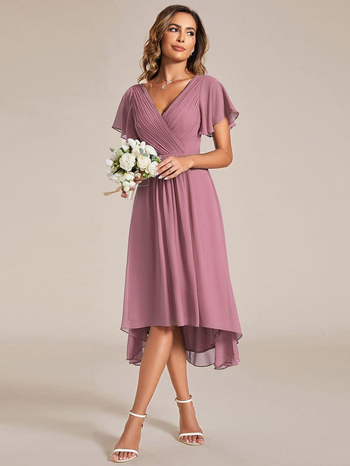 Model im altrosa Chiffonkleid hält einen Strauß weißer Rosen, Blick zur Seite, Vorderansicht mit asymmetrischem Saum. 60