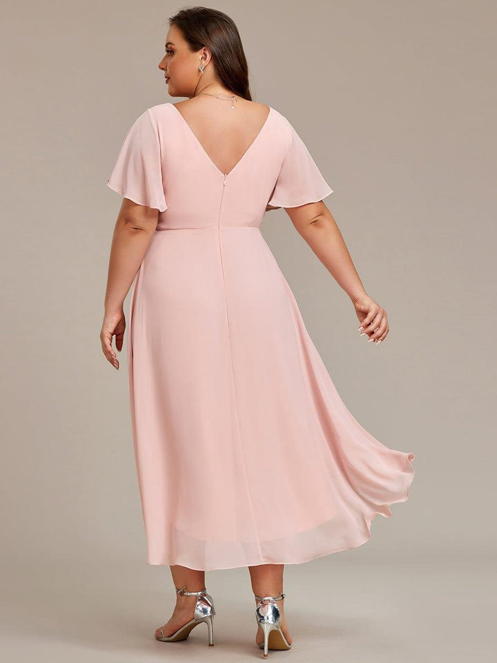 Rückansicht des rosafarbenen Chiffonkleids an einem Curvy Model, tiefer V-Rückenausschnitt mit Reißverschluss und längerem Saum hinten. 32