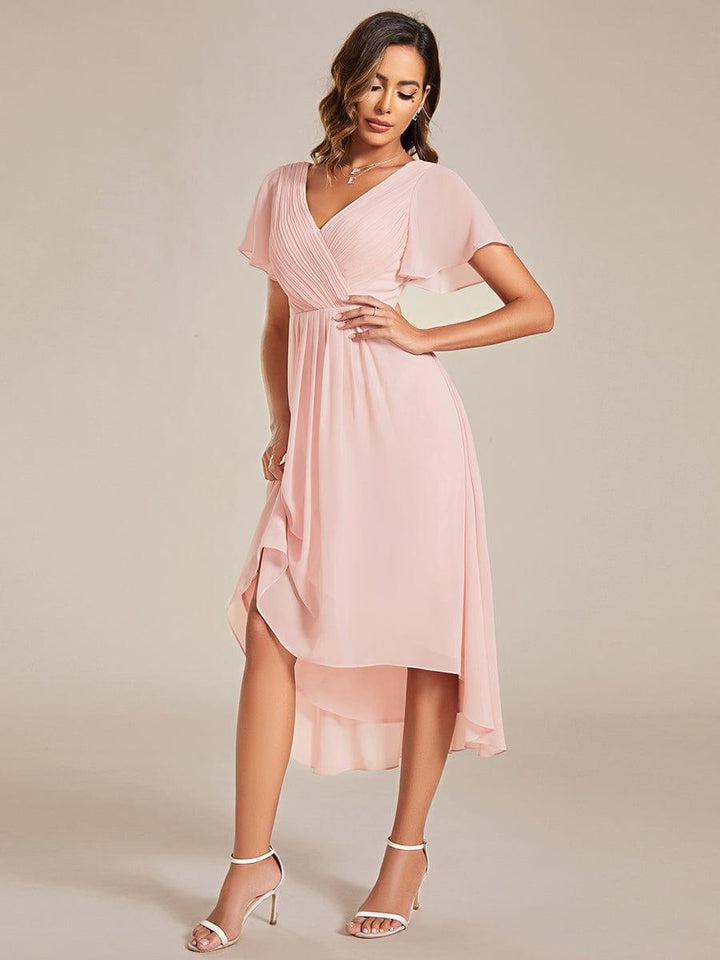 Rosafarbenes Kleid in schräger Ansicht, Model hebt den Rock leicht an, sodass der Hoch-Tief-Saum und die Chiffonlagen sichtbar werden. 19