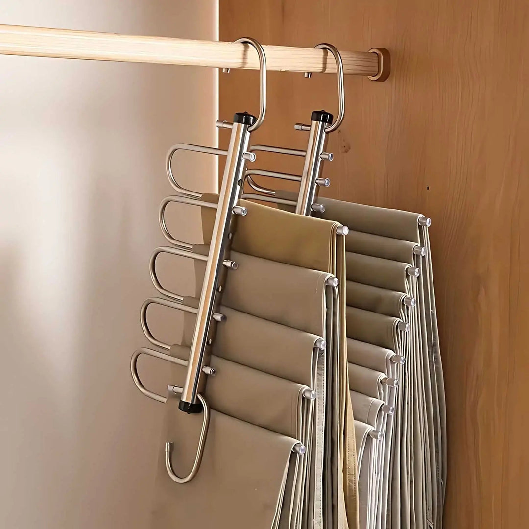 Zwei Edelstahlbügel nebeneinander an der Kleiderstange, links aufgefächert mit fünf Hosen, rechts zusammengeschoben mit mehr Hosen. 4