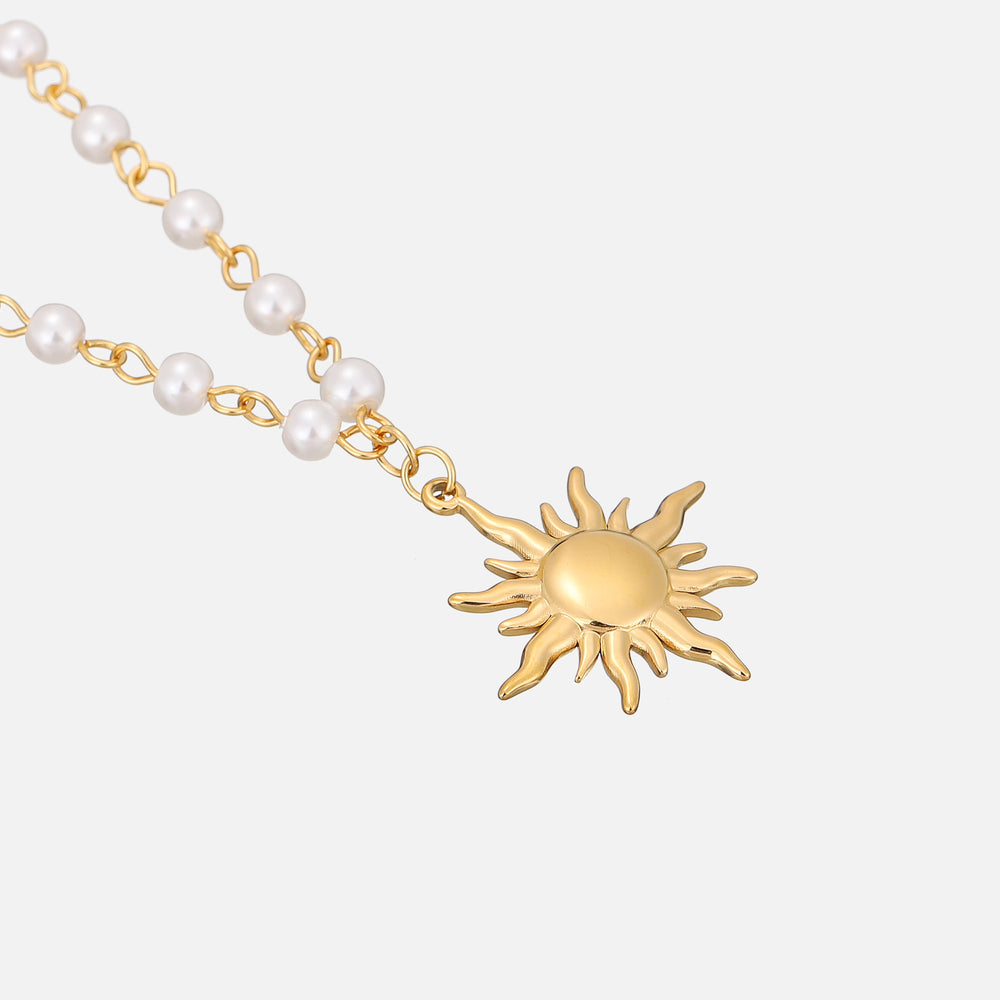 Schräge Nahaufnahme des goldenen Sonnenanhängers mit gewellten Strahlen und der angrenzenden Perlenkette. 2