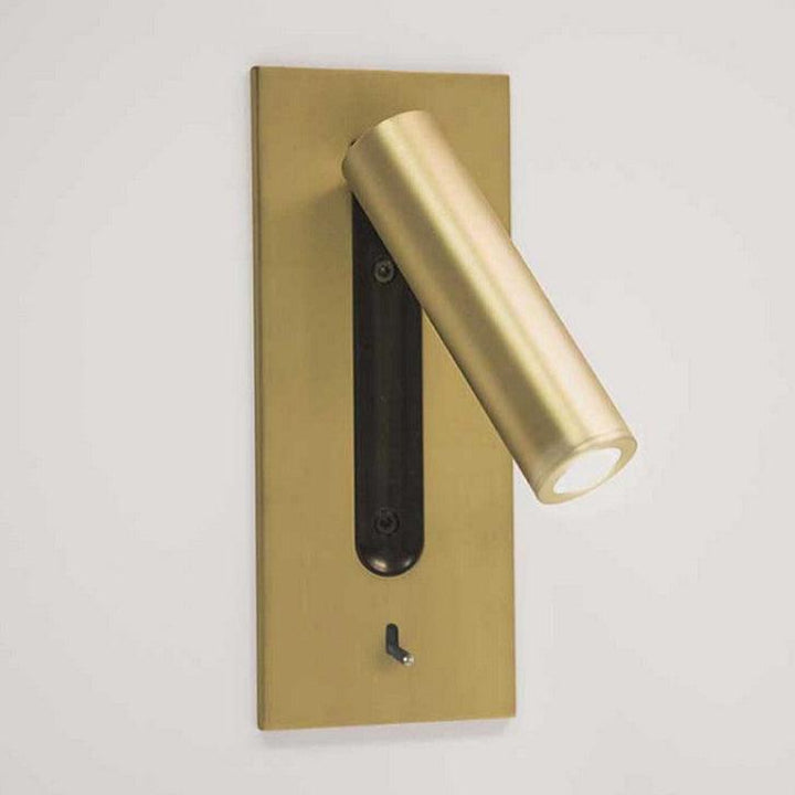 Goldfarbene Wandleuchte mit nach rechts geschwenktem Leuchtenkopf und schwarzer Aussparung 26