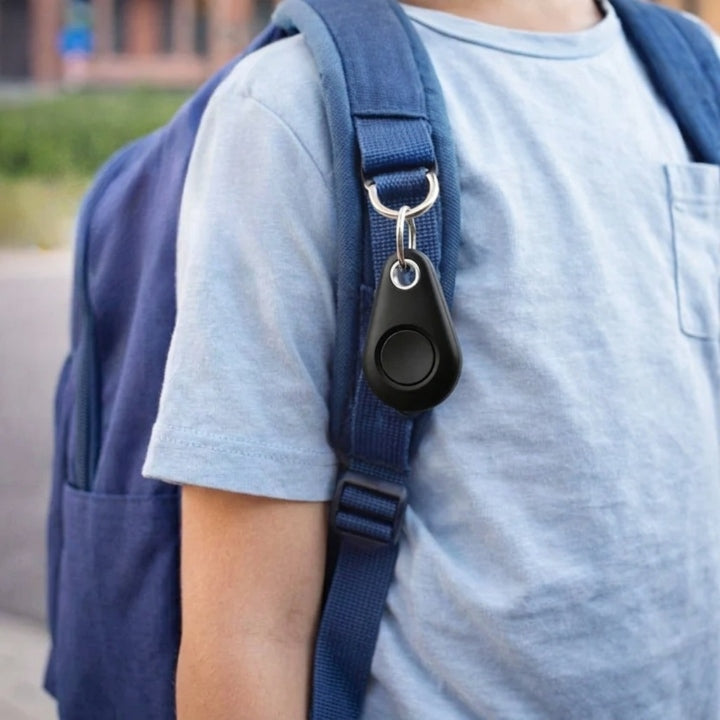 Schwarzer Tracker an einem Karabiner am Schultergurt eines blauen Rucksacks, getragen von einem Kind im hellblauen Shirt 3