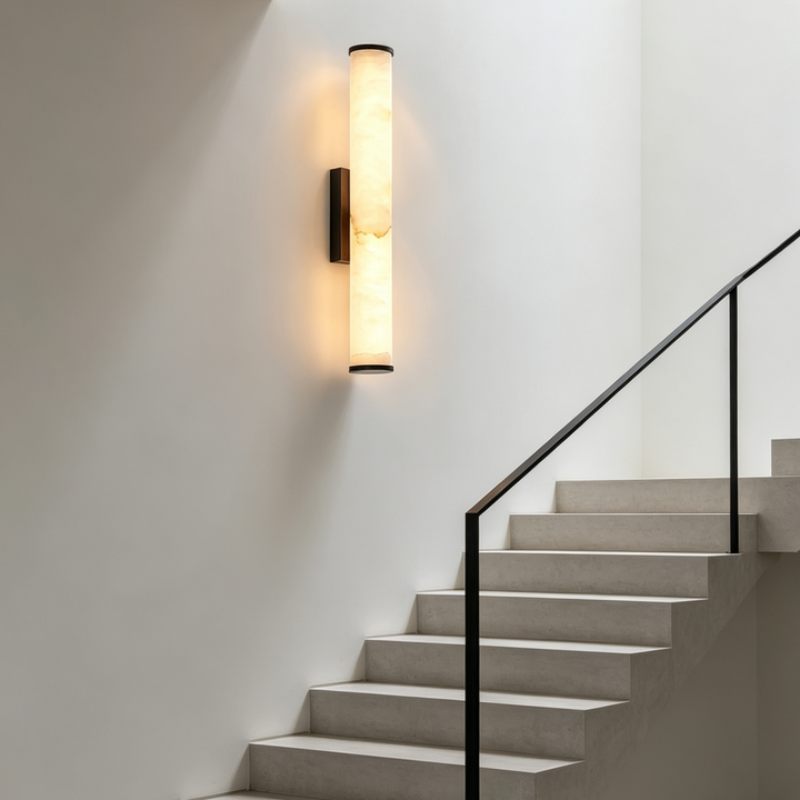 Leuchtende Marmor-Wandleuchte mit dunklen Enden an einer weißen Wand in einem Treppenhaus neben Betontreppe und schwarzem Geländer. 7