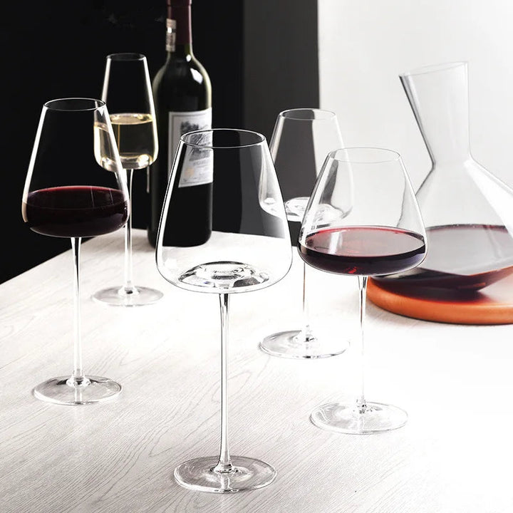 Verschiedene Weingläser mit Rot- und Weißwein neben einer Karaffe auf einem weißen Holztisch 6