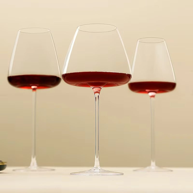 Drei unterschiedlich große Gläser mit Rotwein nebeneinander vor warmem beigem Hintergrund 10