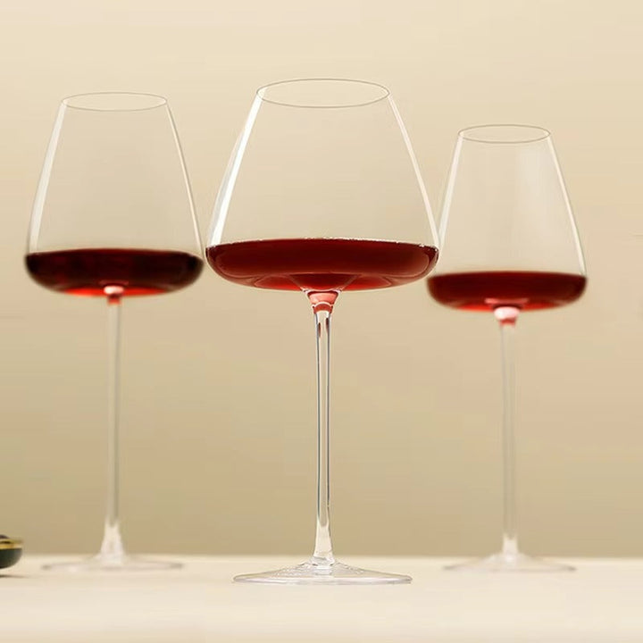 Drei unterschiedlich große Gläser mit Rotwein nebeneinander vor warmem beigem Hintergrund 10