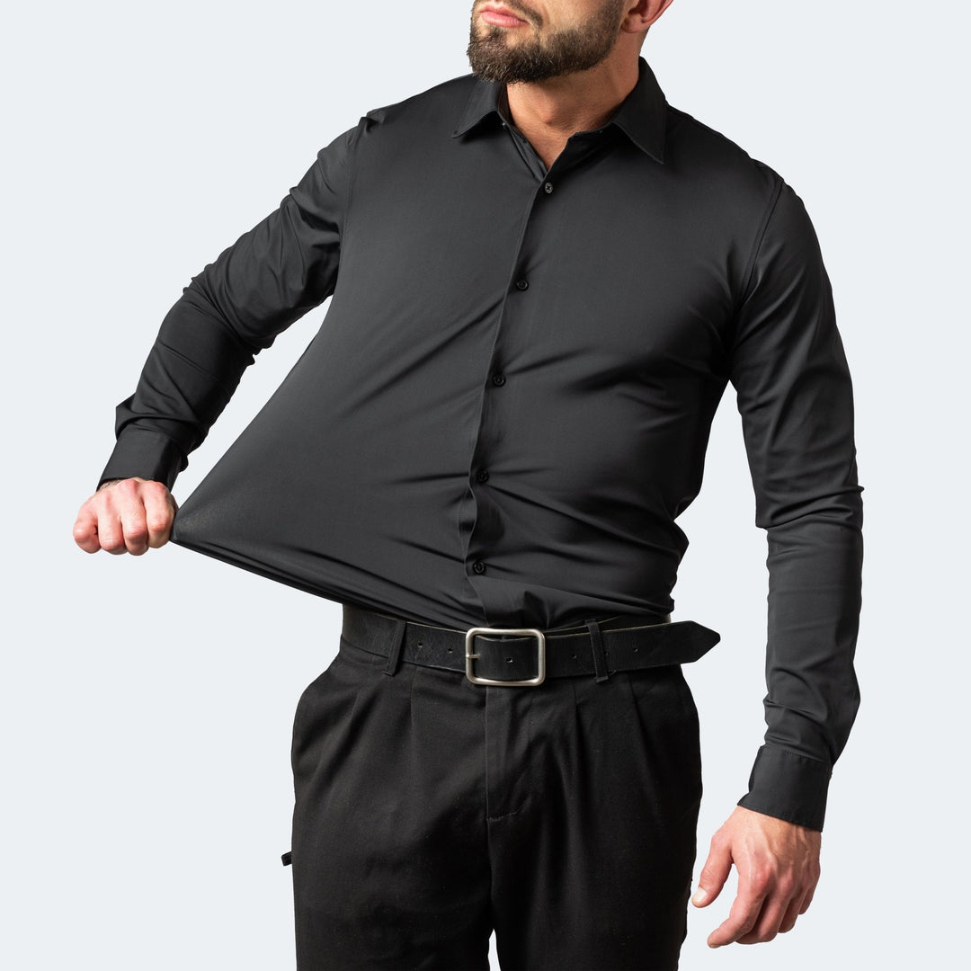 Mann in schwarzem Hemd mit schwarzer Hose zieht den Stoff am Bauch seitlich weit heraus 4
