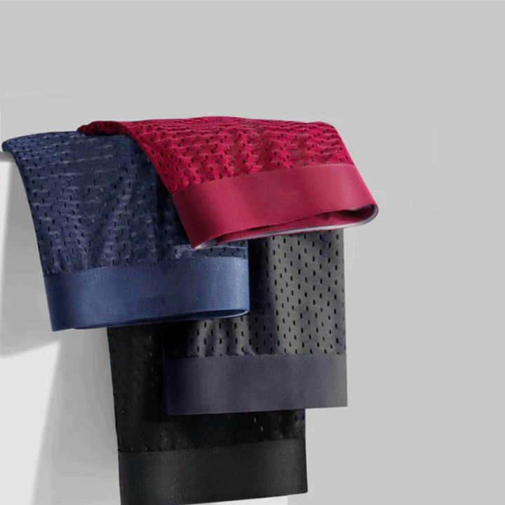 Drei Boxershorts in Rot, Blau und Schwarz mit Netzstruktur und breitem Bund über einer Kante gelegt 3