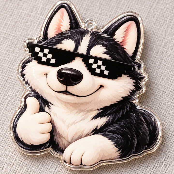 Nahaufnahme eines transparenten Acryl-Anhängers: ein lächelnder Husky mit Pixel-Sonnenbrille zeigt den Daumen nach oben, auf grauem Stoff liegend. 4